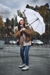 Woman with white umbrella caught in gust of wind on street