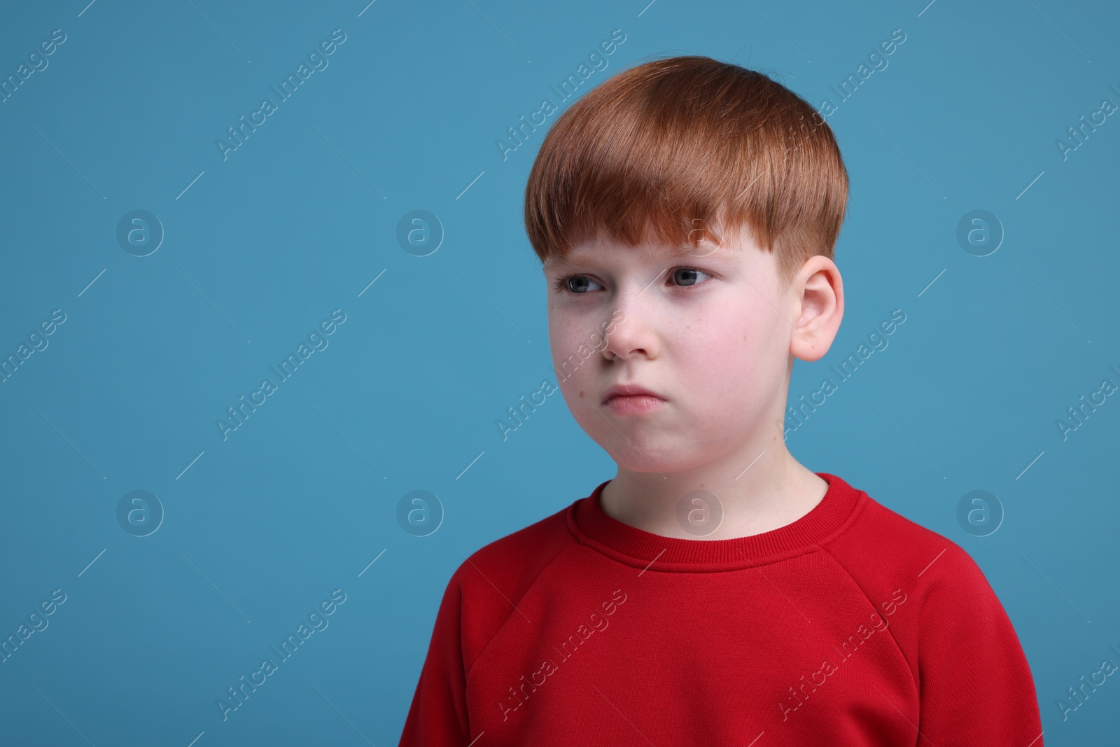 Photo of Portrait of sad little boy on light blue background, space for text