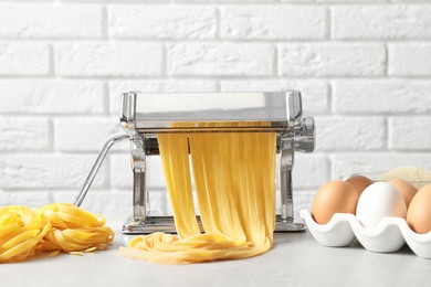 Photo of Pasta maker with dough on kitchen table