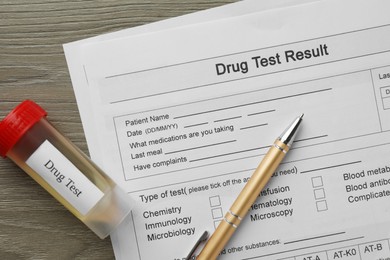 Photo of Drug test result form, container with urine sample and pen on wooden table, flat lay