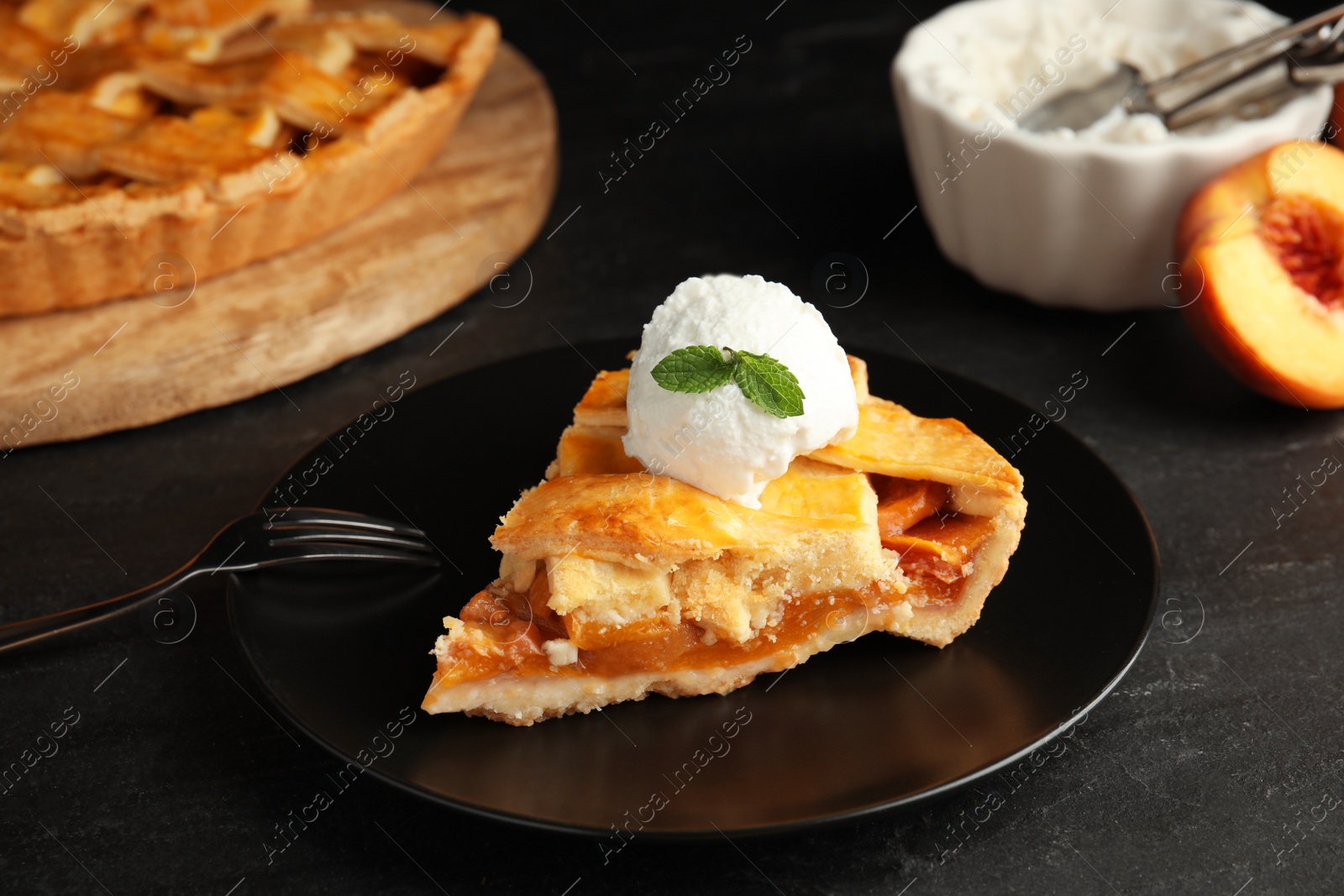 Photo of Slice of delicious peach pie with ice cream on black table