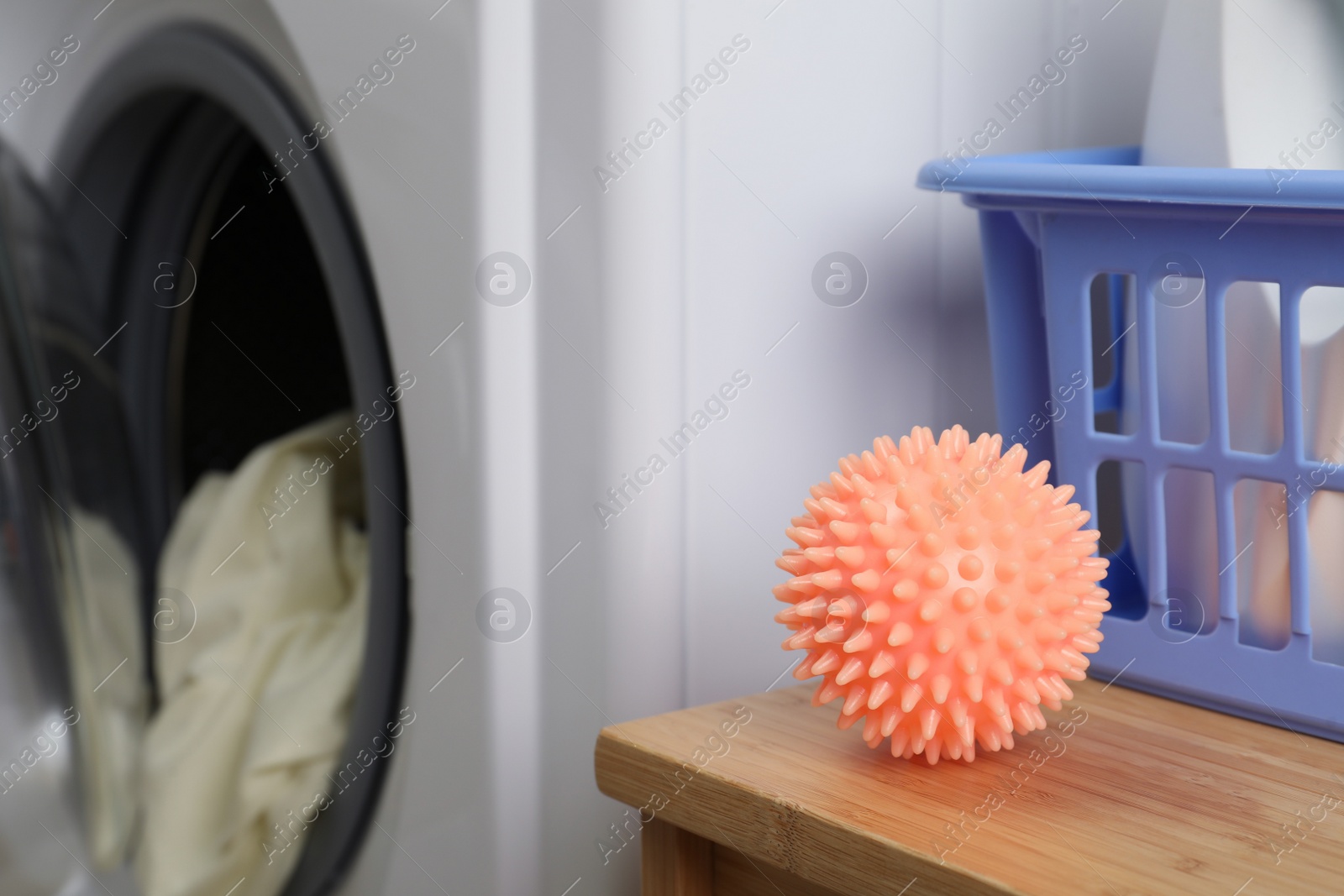 Photo of Orange dryer ball on wooden table near washing machine