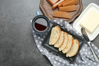 Delicious quince paste, bread, butter and cup of tea on grey table, flat lay. Space for text