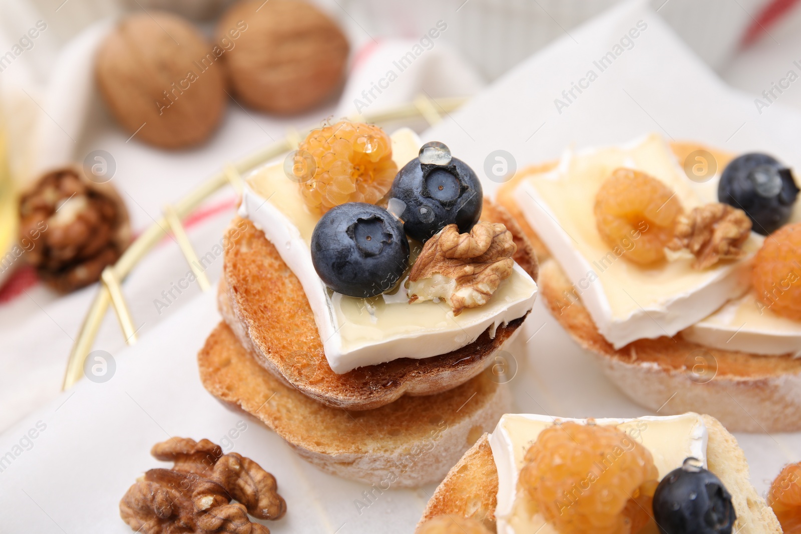 Photo of Tasty sandwiches with brie cheese, fresh berries and walnuts on table, closeup