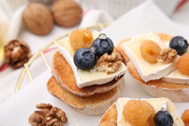 Tasty sandwiches with brie cheese, fresh berries and walnuts on table, closeup