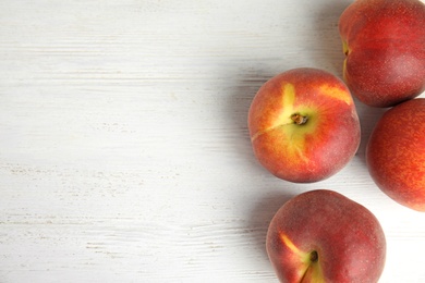 Fresh peaches on white wooden background, top view with space for text