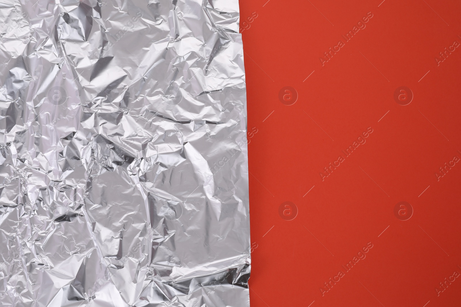 Photo of Sheet of crumpled aluminum foil on orange background, top view. Space for text