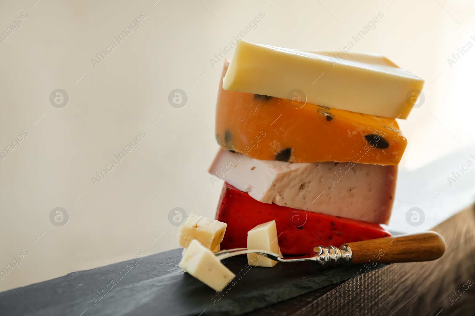 Photo of Different types of delicious cheeses and fork on slate plate, closeup. Space for text
