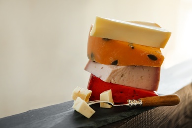 Photo of Different types of delicious cheeses and fork on slate plate, closeup. Space for text