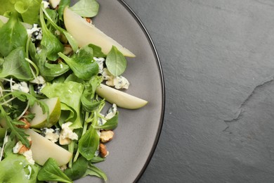 Photo of Tasty salad with pear slices on black table, top view. Space for text