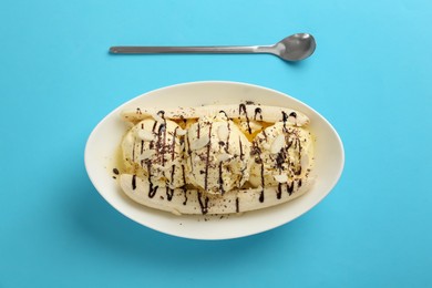 Photo of Delicious banana split ice cream with toppings on light blue background, flat lay