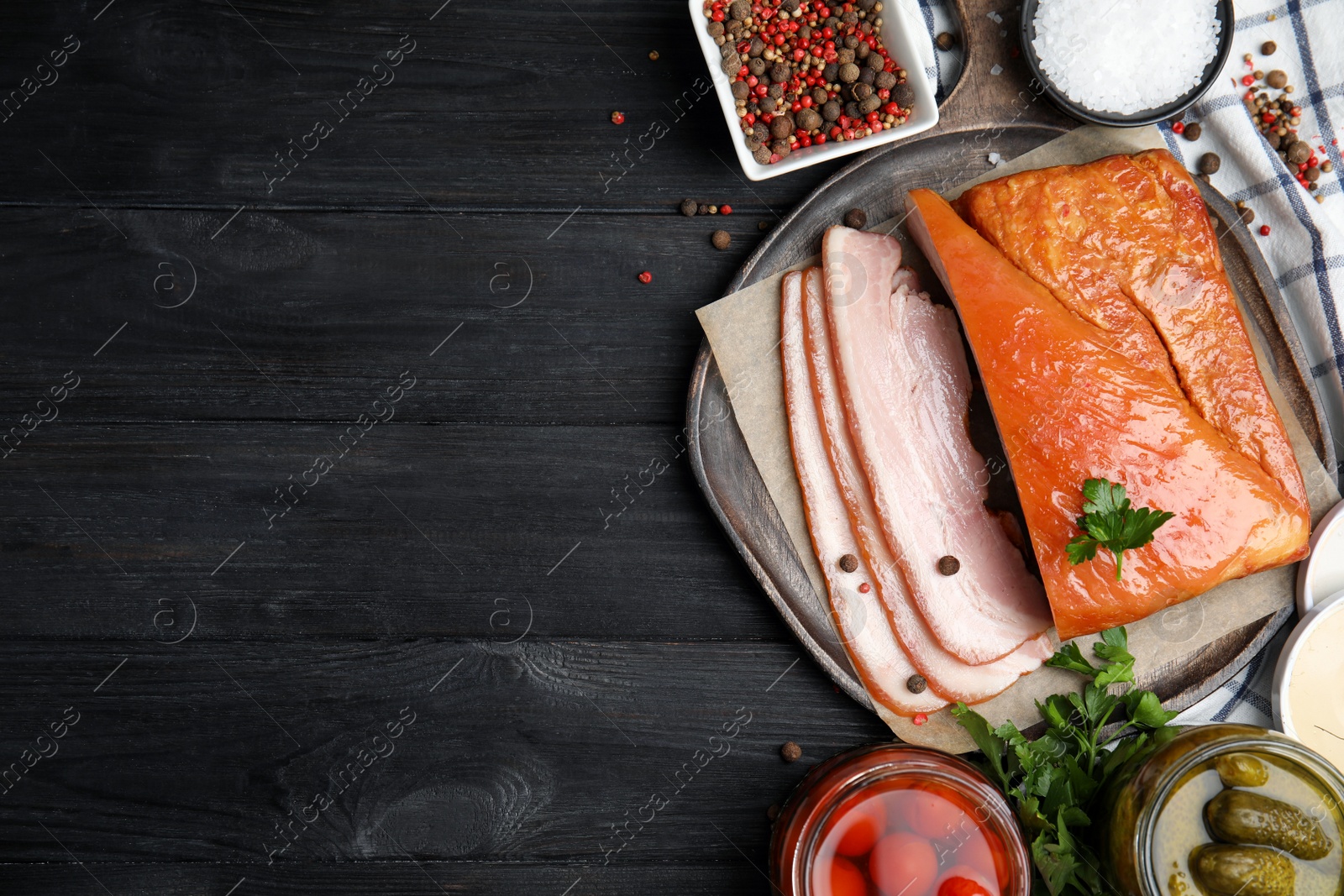 Photo of Flat lay composition with delicious smoked bacon on black wooden table, space for text