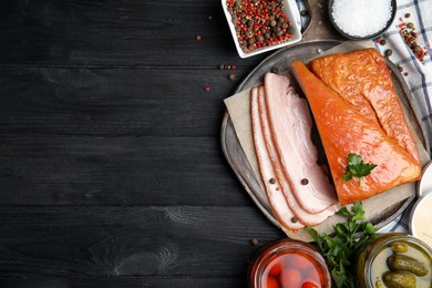 Photo of Flat lay composition with delicious smoked bacon on black wooden table, space for text