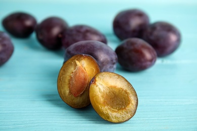 Delicious ripe plums on light blue wooden table, closeup