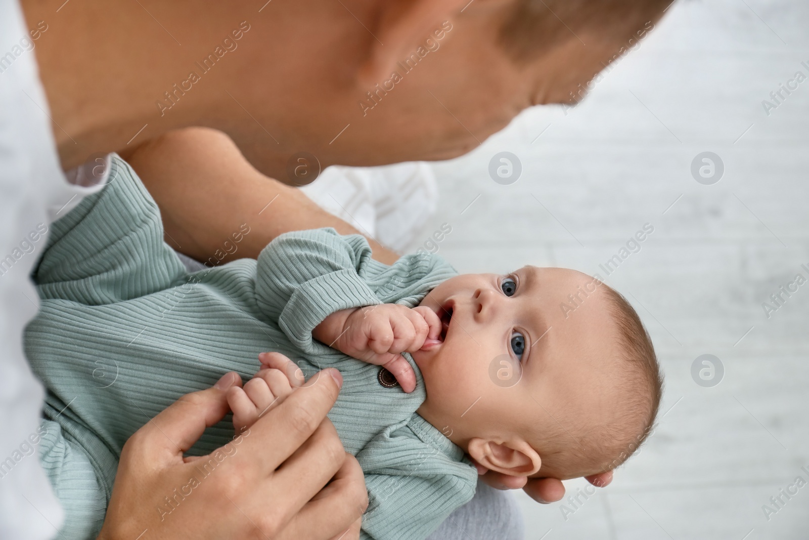 Photo of Father holding his cute baby indoors, above view