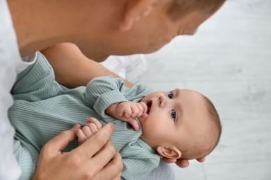 Father holding his cute baby indoors, above view