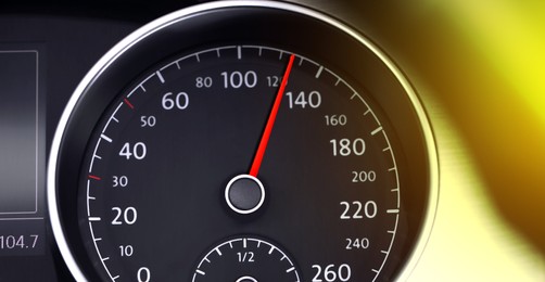 Image of Speedometer on car dashboard under yellow light, closeup. Banner design