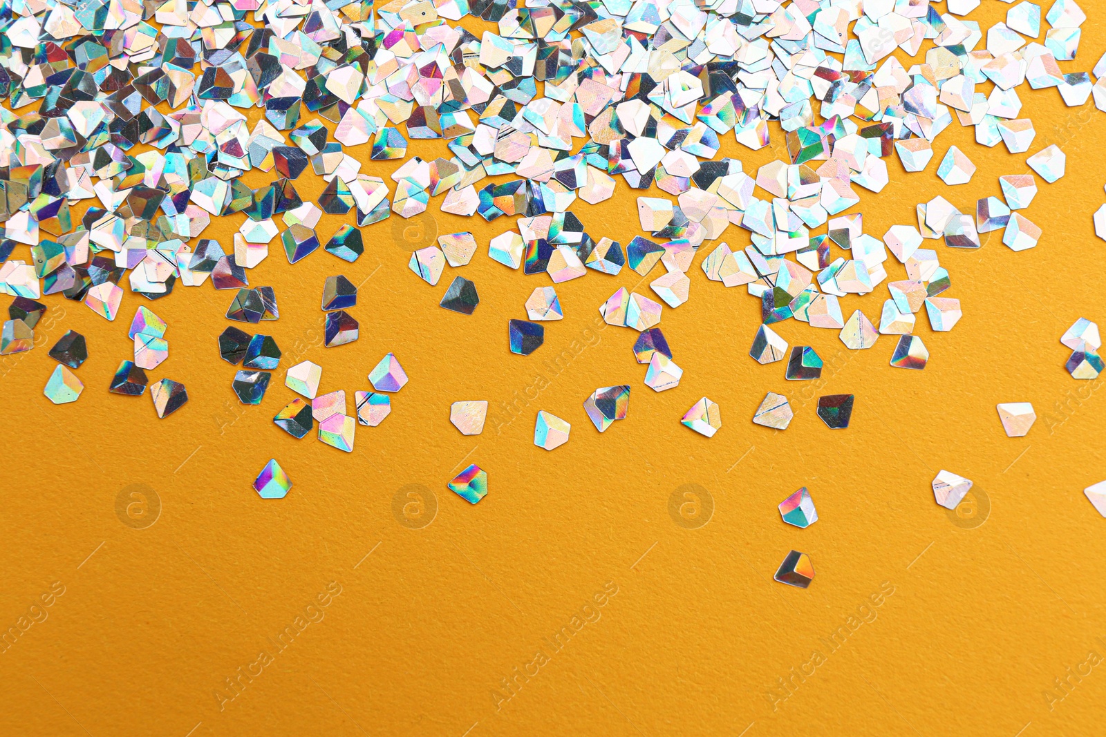 Photo of Shiny bright glitter on orange background. Space for text