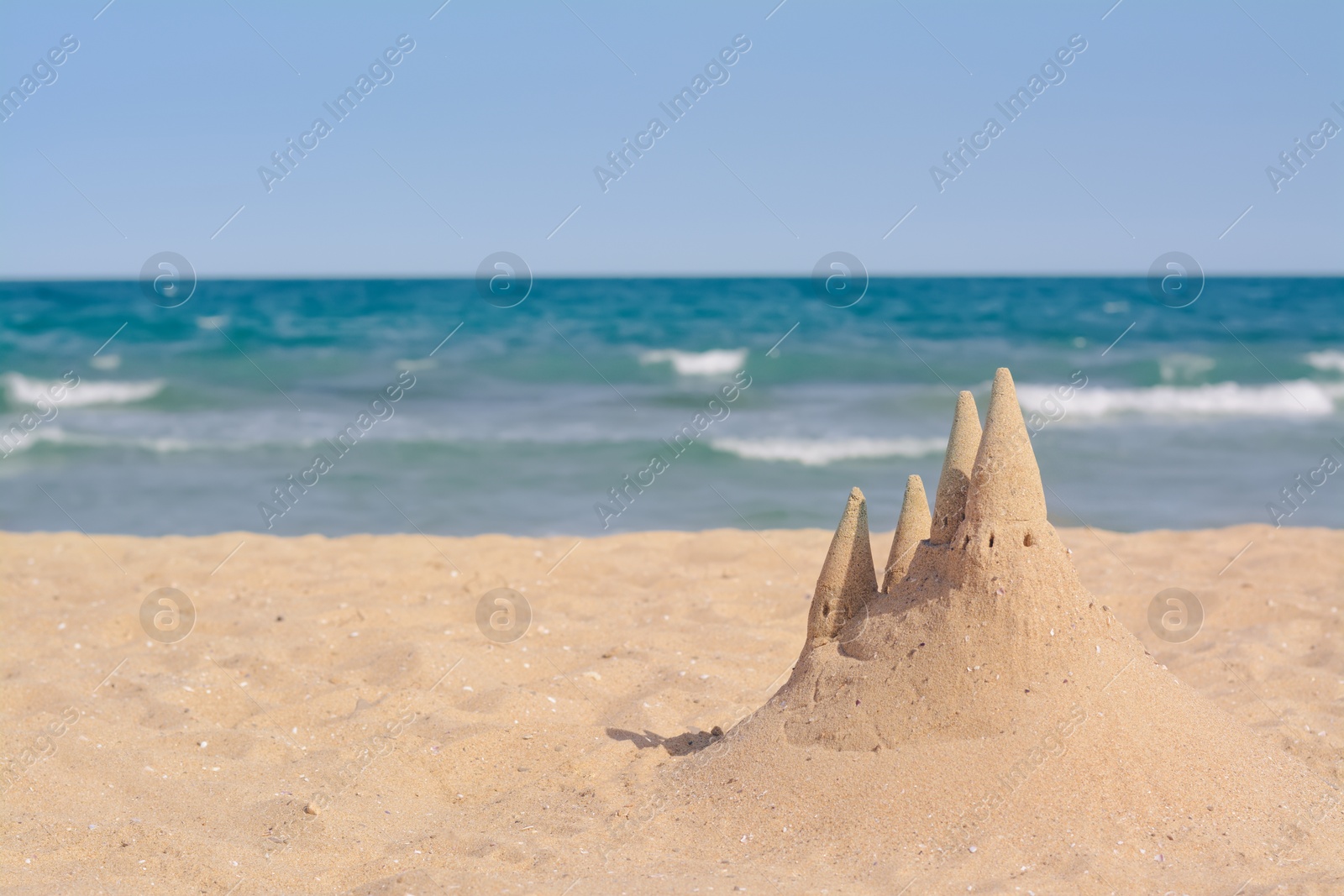 Photo of Beach with sand castle near sea on sunny day. Space for text