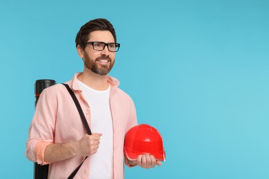 Architect with drawing tube and hard hat on light blue background, space for text