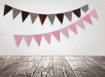 Image of Empty wooden table and decorative bunting flags hanging on white wall