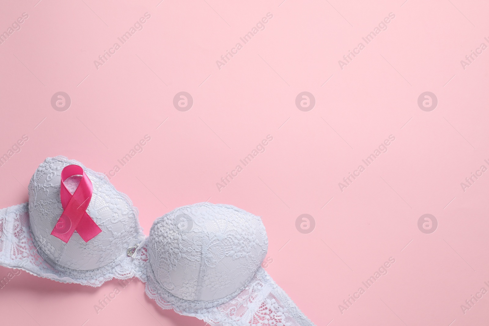 Photo of Pink ribbon and bra on color background, top view with space for text. Breast cancer awareness