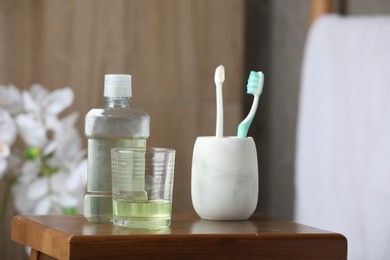 Photo of Mouthwash and toothbrushes on wooden table in bathroom