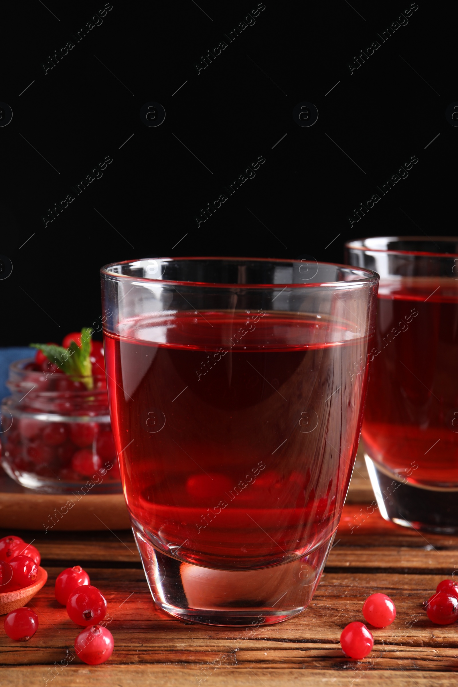 Photo of Tasty cranberry juice in glasses and fresh berries on wooden table