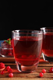 Tasty cranberry juice in glasses and fresh berries on wooden table