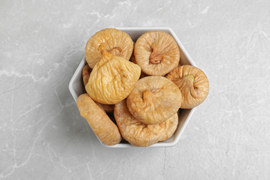 Photo of Tasty dried figs in bowl on light grey table, top view