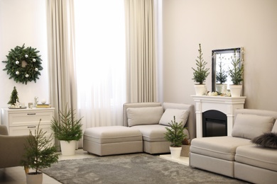 Stylish living room interior with little fir trees and Christmas decorations