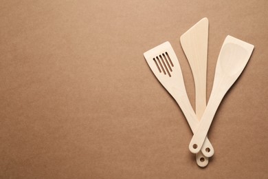 Photo of Different wooden spatulas on brown background, flat lay. Space for text