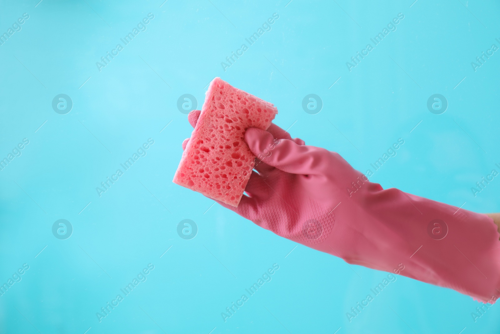 Photo of Woman cleaning glass against color background