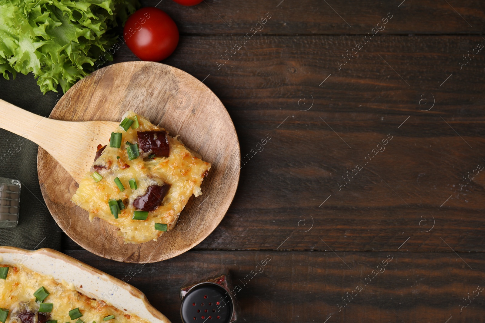 Photo of Tasty sausage casserole served on wooden table, flat lay. Space for text