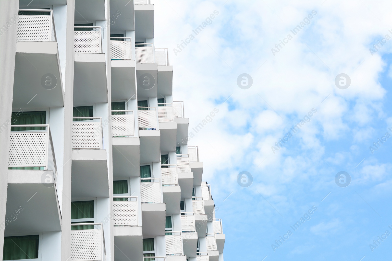 Photo of Exterior of beautiful building with balconies against blue sky, low angle view. Space for text