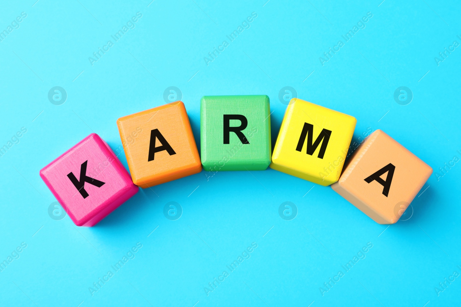 Photo of Word Karma made of colorful cubes with letters on light blue background, top view