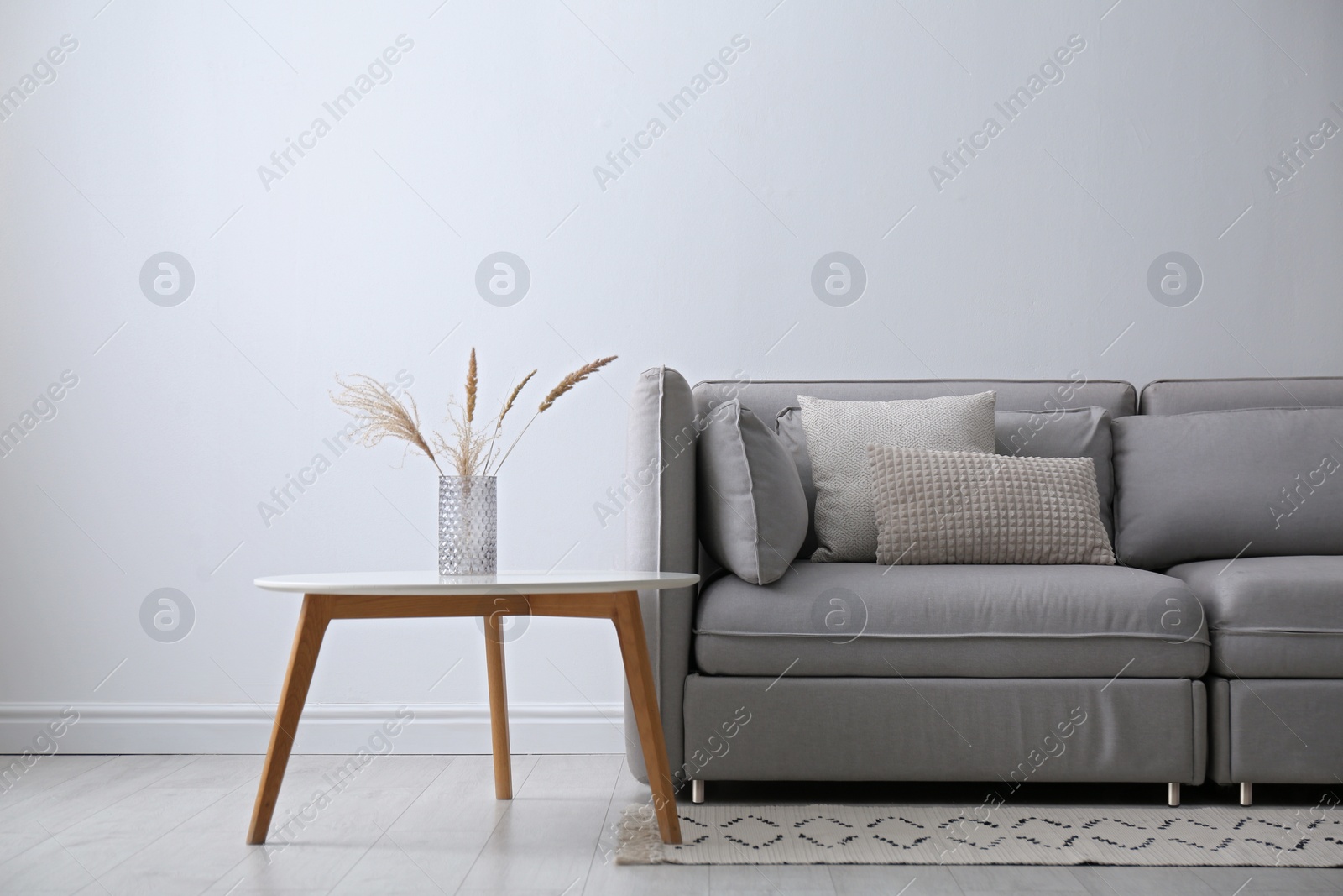 Photo of Grey sofa with pillows near white wall in stylish living room interior