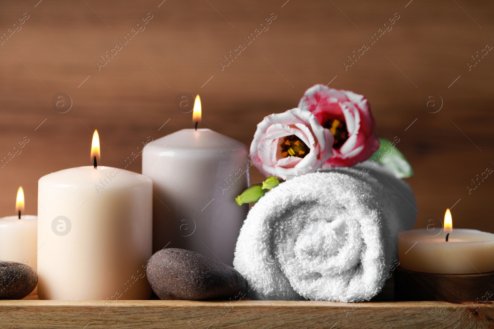 Photo of Beautiful composition with spa stones, flowers and burning candles on wooden table