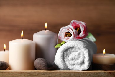 Photo of Beautiful composition with spa stones, flowers and burning candles on wooden table