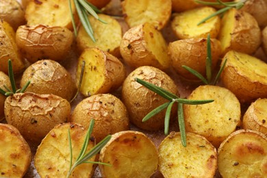 Delicious baked potatoes with rosemary as background, closeup