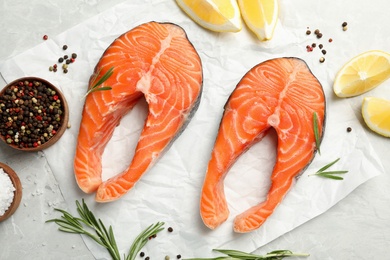 Photo of Fresh salmon steaks with spices, lemon and rosemary on marble table, flat lay