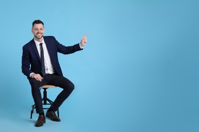 Photo of Handsome businessman sitting in office chair on light blue background