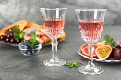 Photo of Delicious exotic fruits and wine on grey table