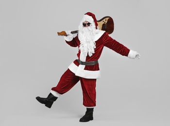 Photo of Santa Claus with electric guitar on light grey background. Christmas music