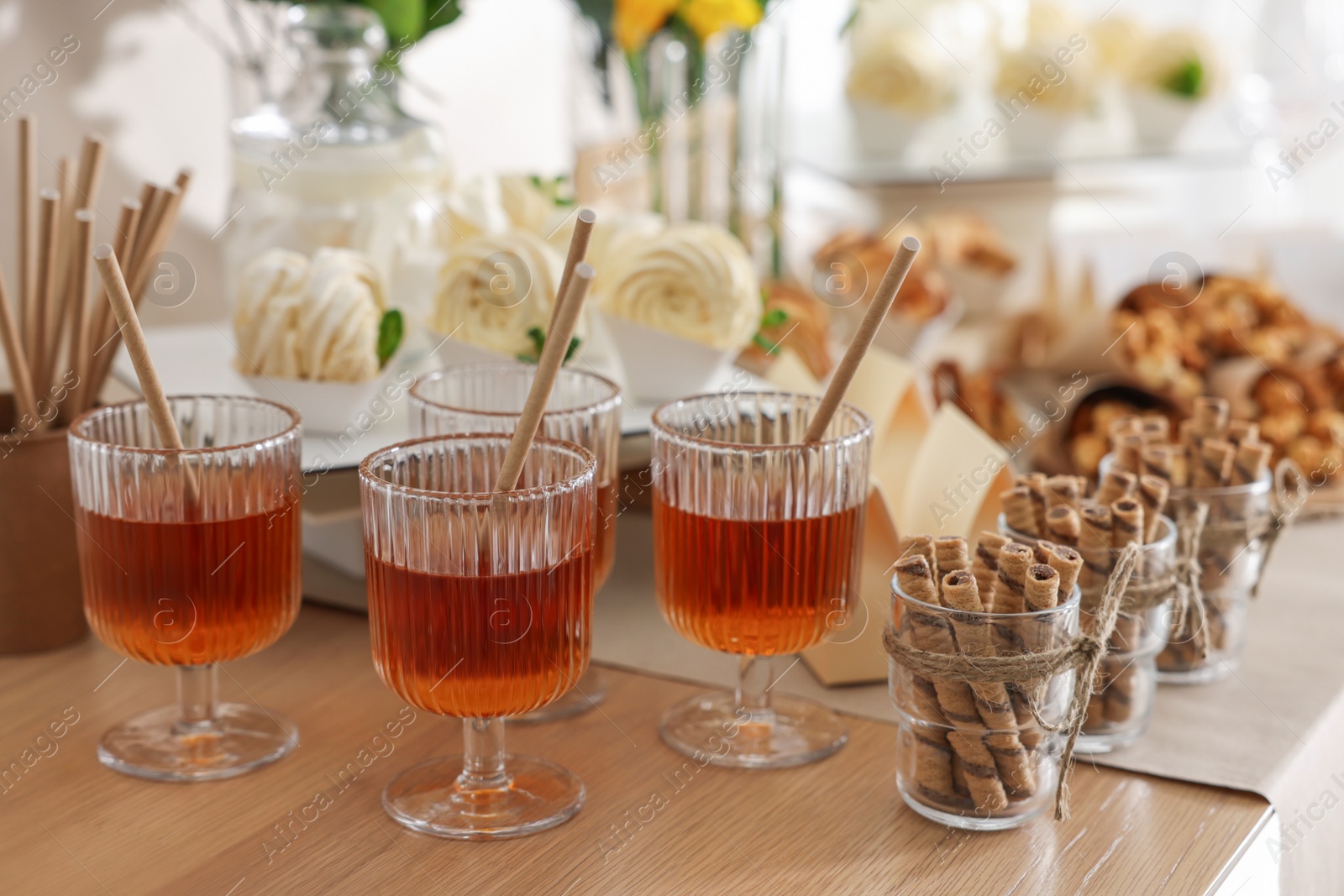 Photo of Delicious treats and glasses of drink on wooden table. Sweet buffet