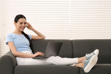 Happy woman working with laptop on sofa at home