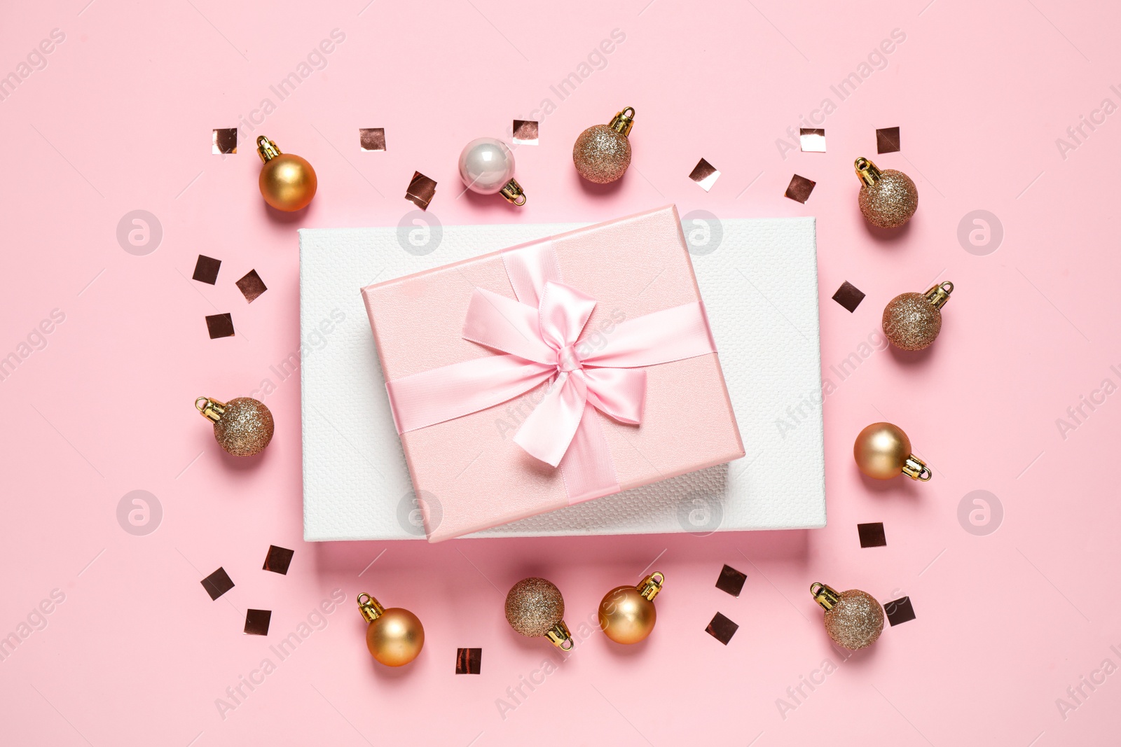 Photo of Beautiful gift boxes, golden Christmas balls and confetti on pink background, flat lay