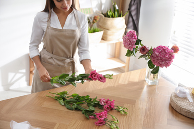 Photo of Florist making beautiful bouquet at table in workshop, closeup