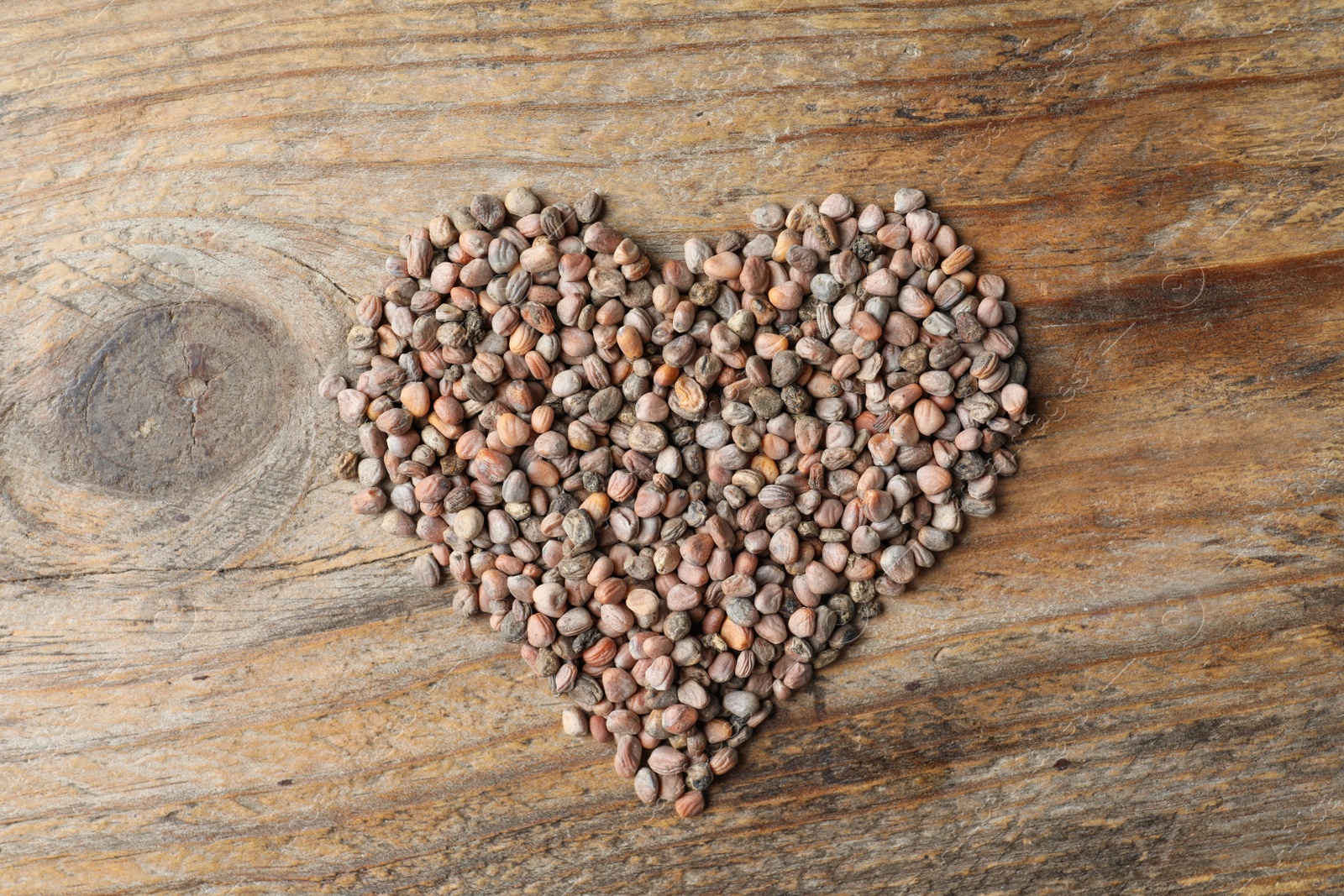 Photo of Heart made of raw radish seeds on wooden background, top view. Vegetable planting