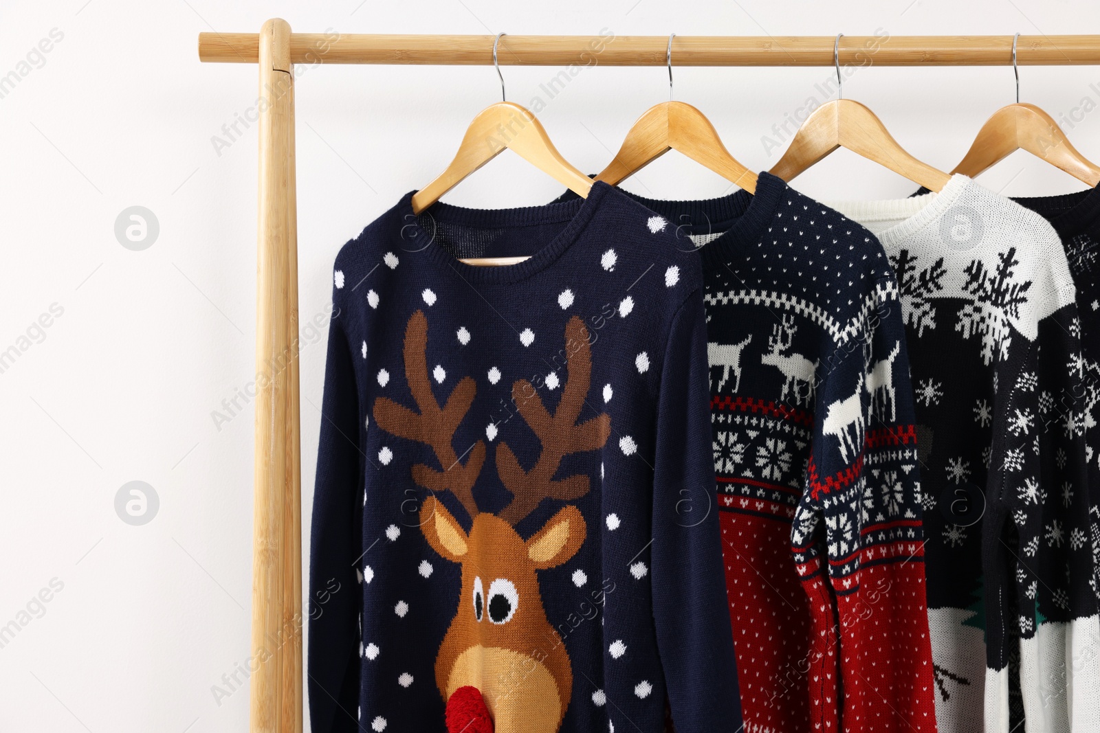 Photo of Rack with different Christmas sweaters on white background